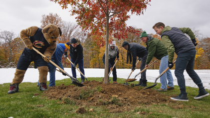 The Cleveland Cavaliers mascot planting a tree with six other men.