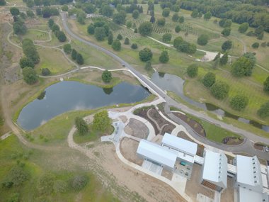 An aerial view of a large property with trees, trails, a pond and a large facility.
