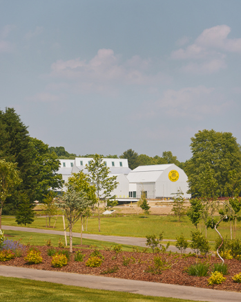A white facility behind grass and paths