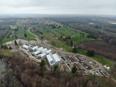 An aerial view of a large property with many trees, trails and a large facility.